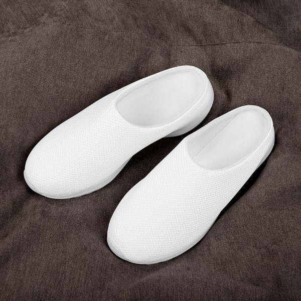 A pair of white home slippers are placed on a brown blanket