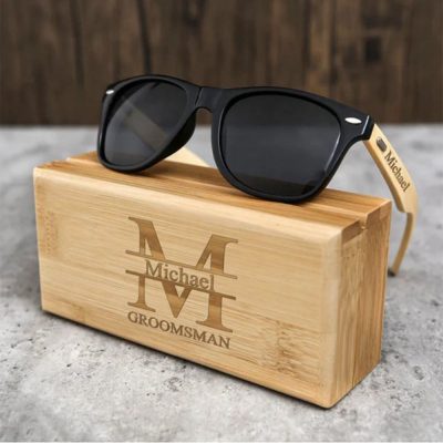 A pair of wooden sunglasses are placed on a wooden lettered case.