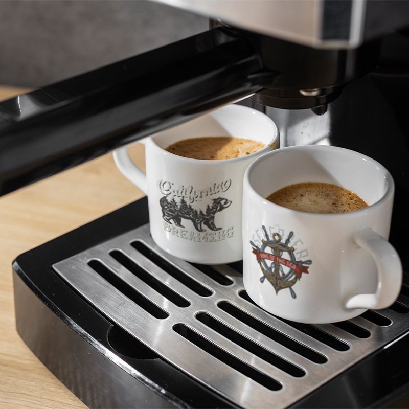 Two coffee cups are being filled with coffee under the coffee machine