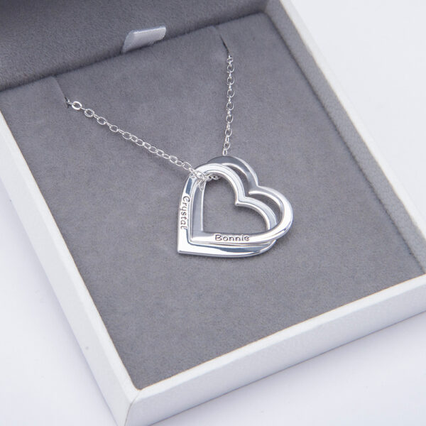 A silver heart necklace is placed in a jewelry box