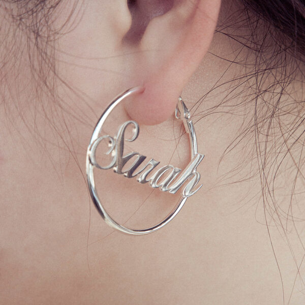 A female model wears a pair of silver hoop earrings