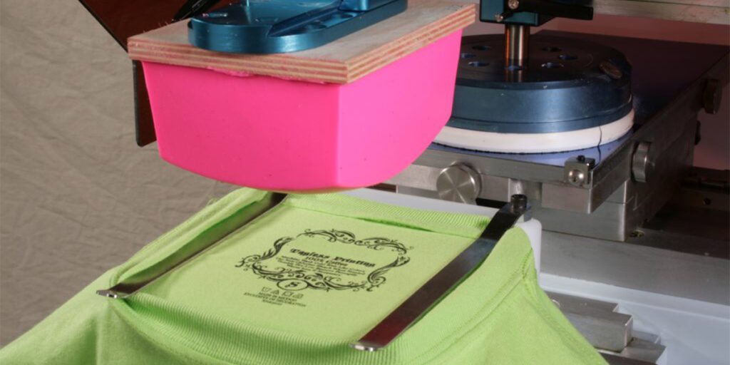 A pad printing machine is printing green clothes