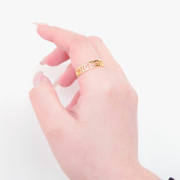 A woman's hand wearing a gold ring with Roman numerals