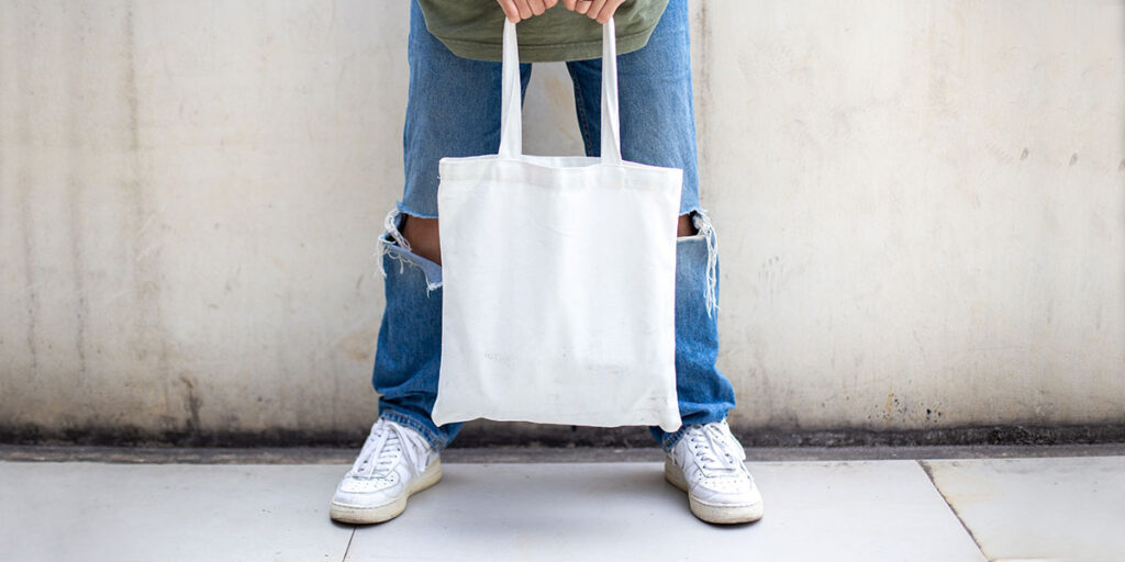 A man is holding a white tote bag